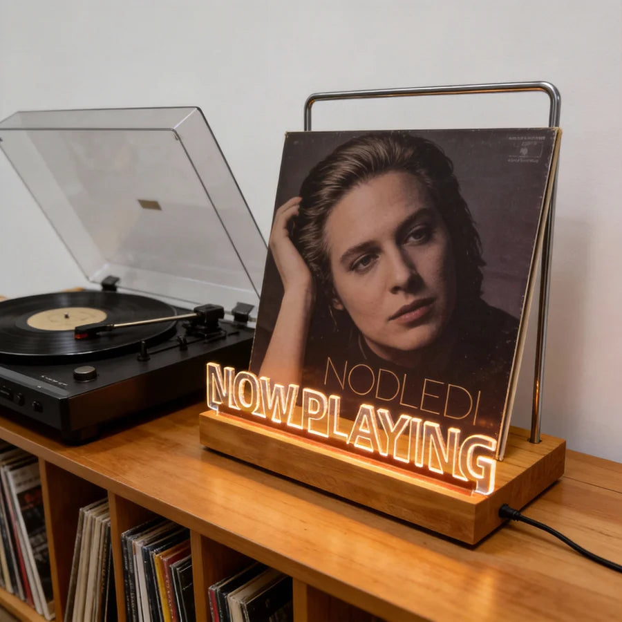 Vinyl record on a 'Now Playing' stand with a turntable in the background
