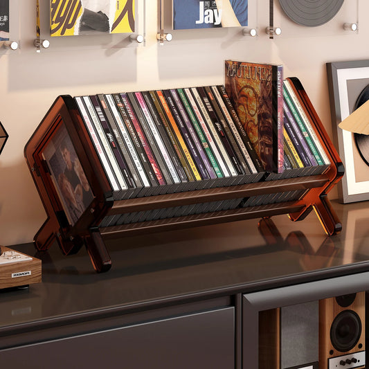 Acrylic CD holder with CDs on a shelf against a wall with framed pictures.