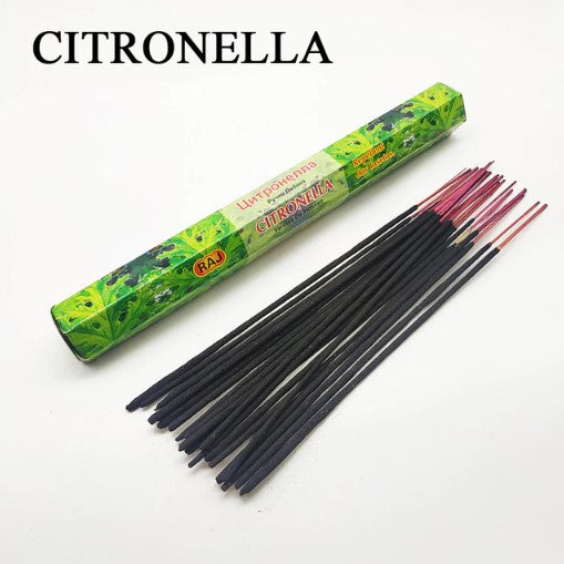 A green rectangular box labeled "Citronella" next to a scattered group of dark incense sticks with red tips on a white surface.