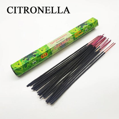 A green rectangular box labeled "Citronella" next to a scattered group of dark incense sticks with red tips on a white surface.